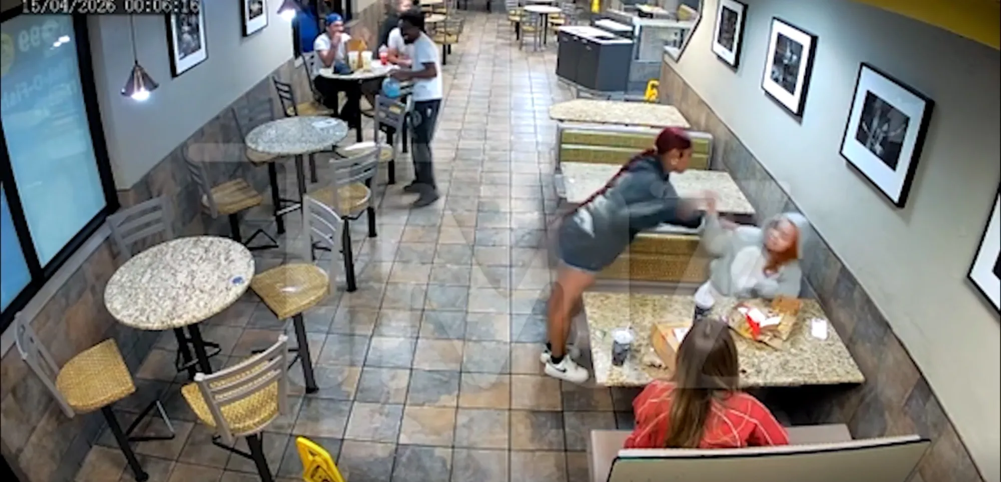 A woman in a black dress slapping another woman in a gray hoodie inside a McDonald's.