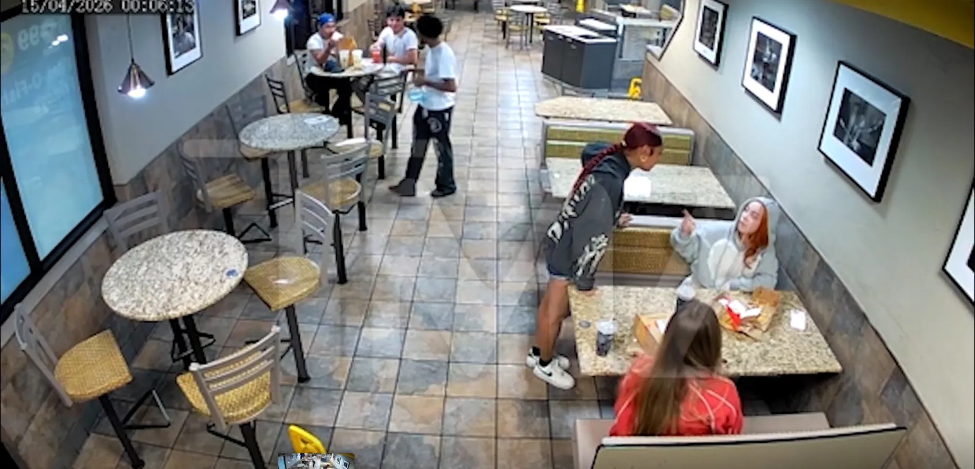 Two women sitting at a table in a McDonald's, one pointing at the other, while another woman stands over them.