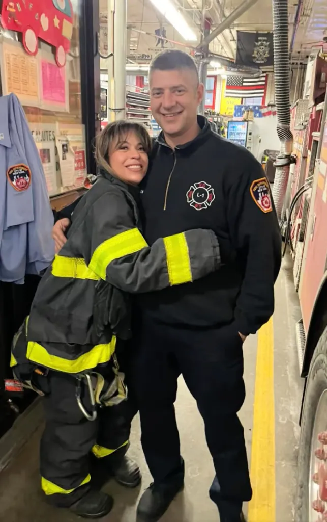 A woman in a firefighter's suit hugs a male firefighter.