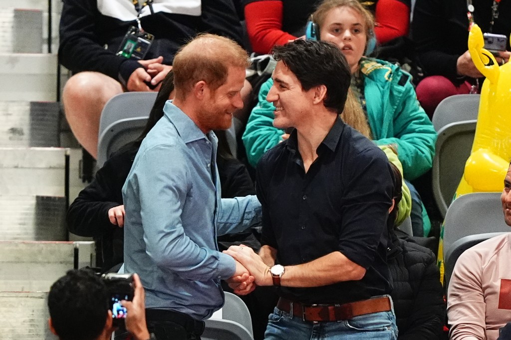 Prince Harry and Justin Trudeau shaking hands and smiling at each other.