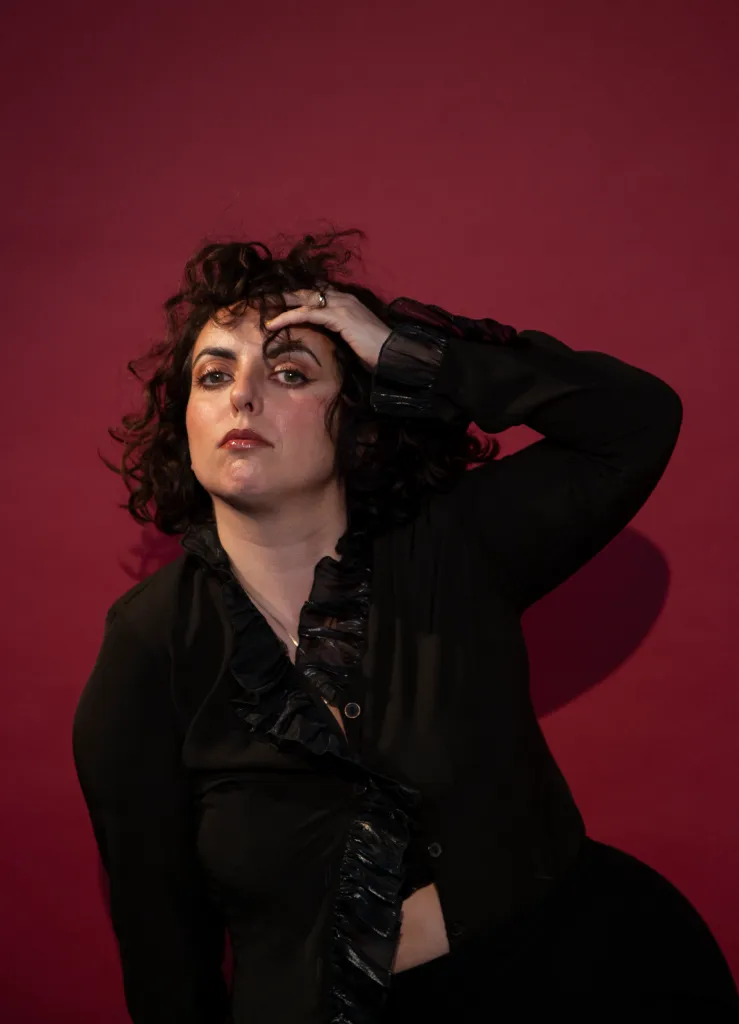 Effie Spence posing with a hand to her head, looking at the camera.