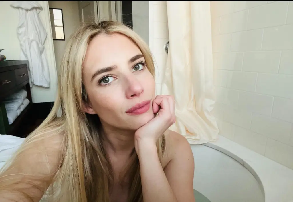 Emma Roberts in a bathtub, looking at the camera.