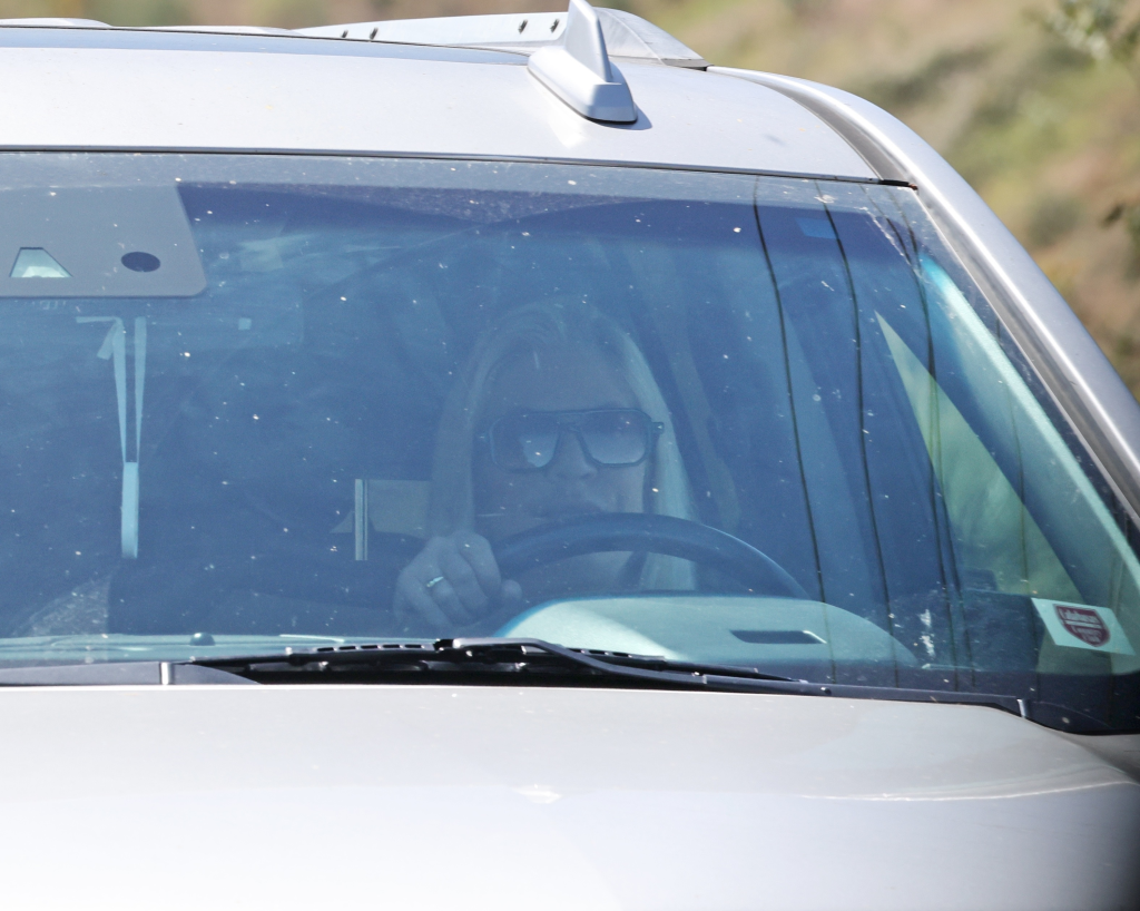 Tori Spelling driving her damaged SUV while wearing sunglasses.