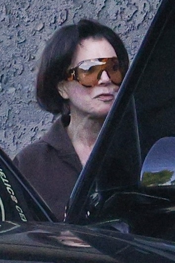 Kris Jenner wearing large orange sunglasses and a brown shirt.