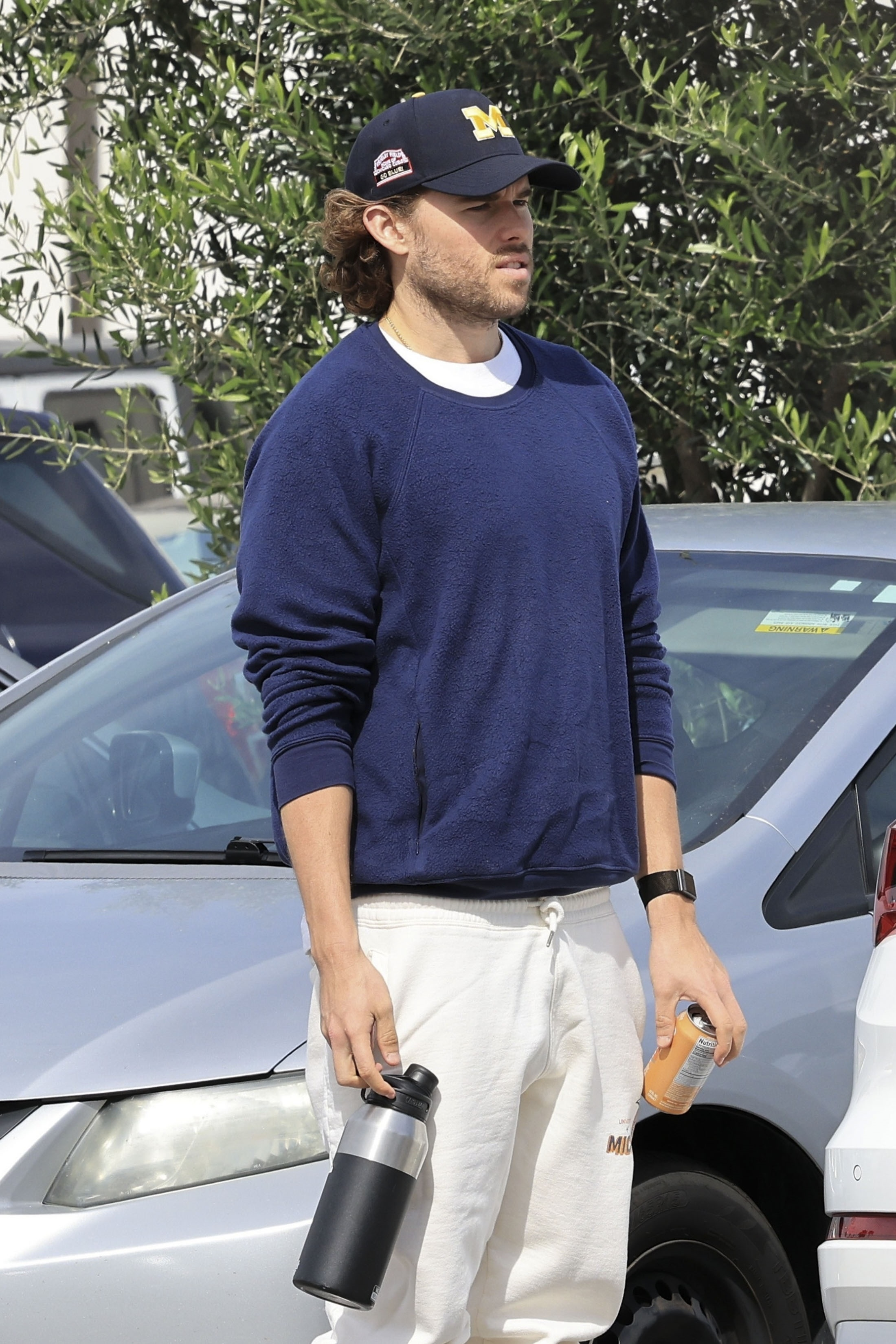 Christopher Schwarzenegger in a navy crewneck sweatshirt, off-white joggers, and a baseball cap in Malibu.