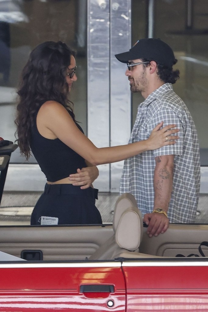 Joe Jonas and Tatiana Gabriela embracing in a red BMW convertible.