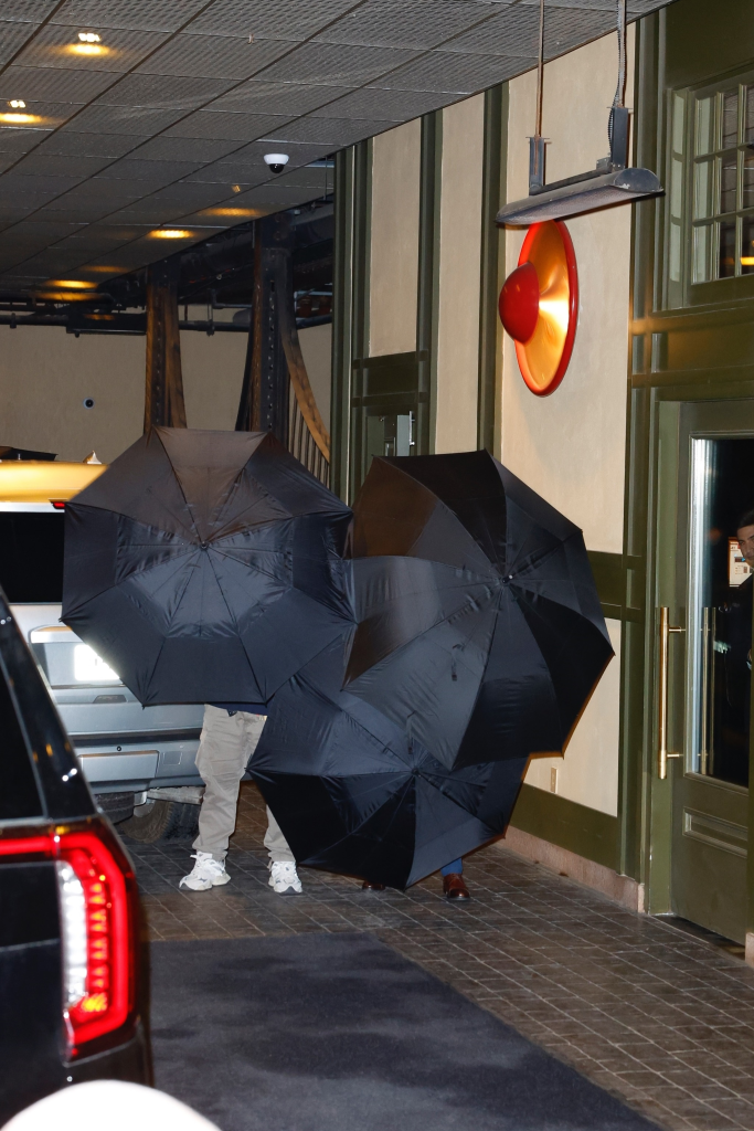Taylor Swift and Travis Kelce hide behind umbrellas as they arrive at Casa Cipriani in NYC.