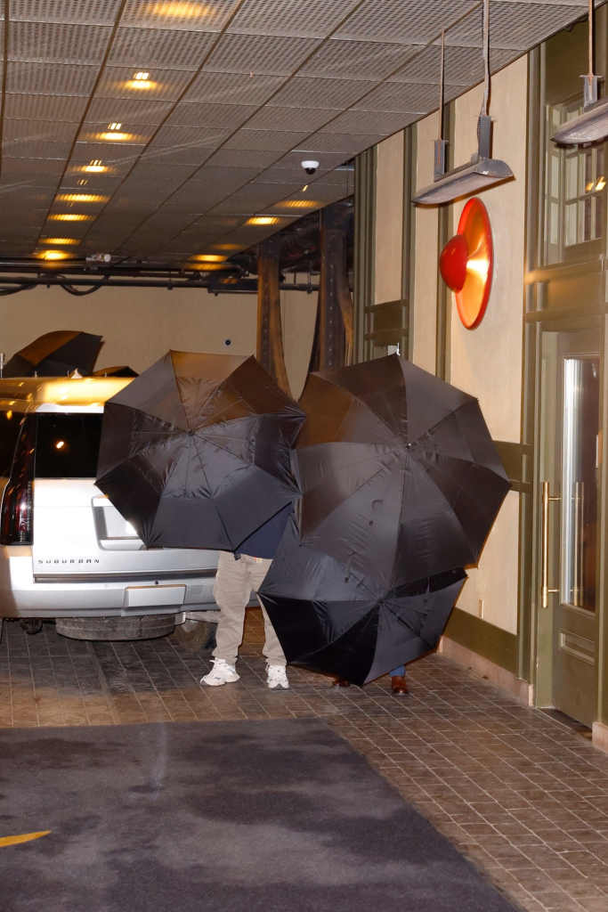 Taylor Swift and Travis Kelce hiding behind two black umbrellas while arriving at Casa Cipriani in NYC.