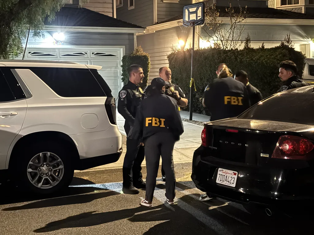 Police officers stand on the street outside the home of WHCD shooting suspect Cole Allen in Torrance, California.