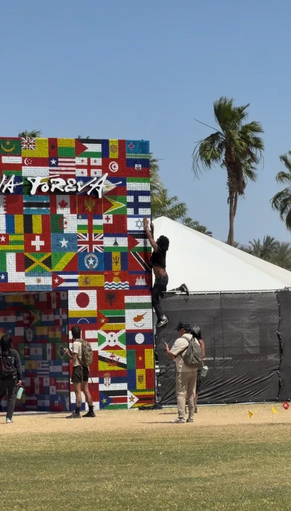 A man attempts to rip off the Israeli flag from an art installation, while standing on a fence.