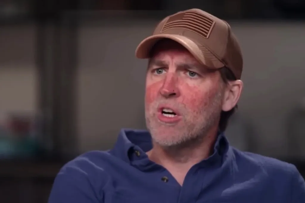 Former Republican Sen. Ben Sasse, wearing a baseball cap with a US flag design, speaks.