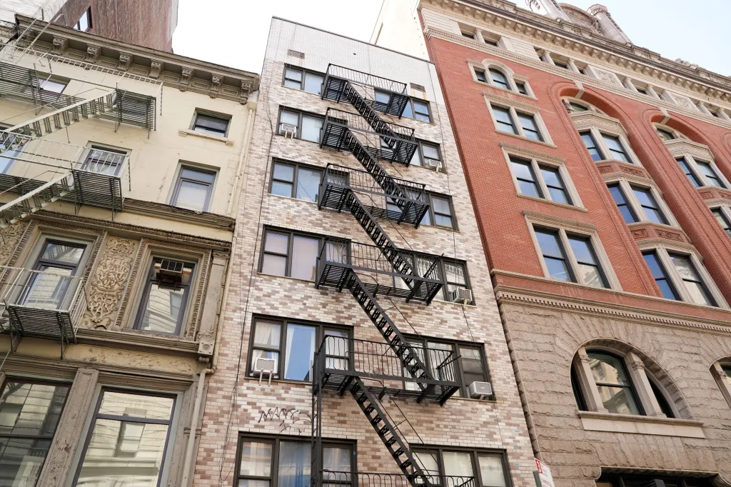 Three apartment buildings in New York City with fire escapes.