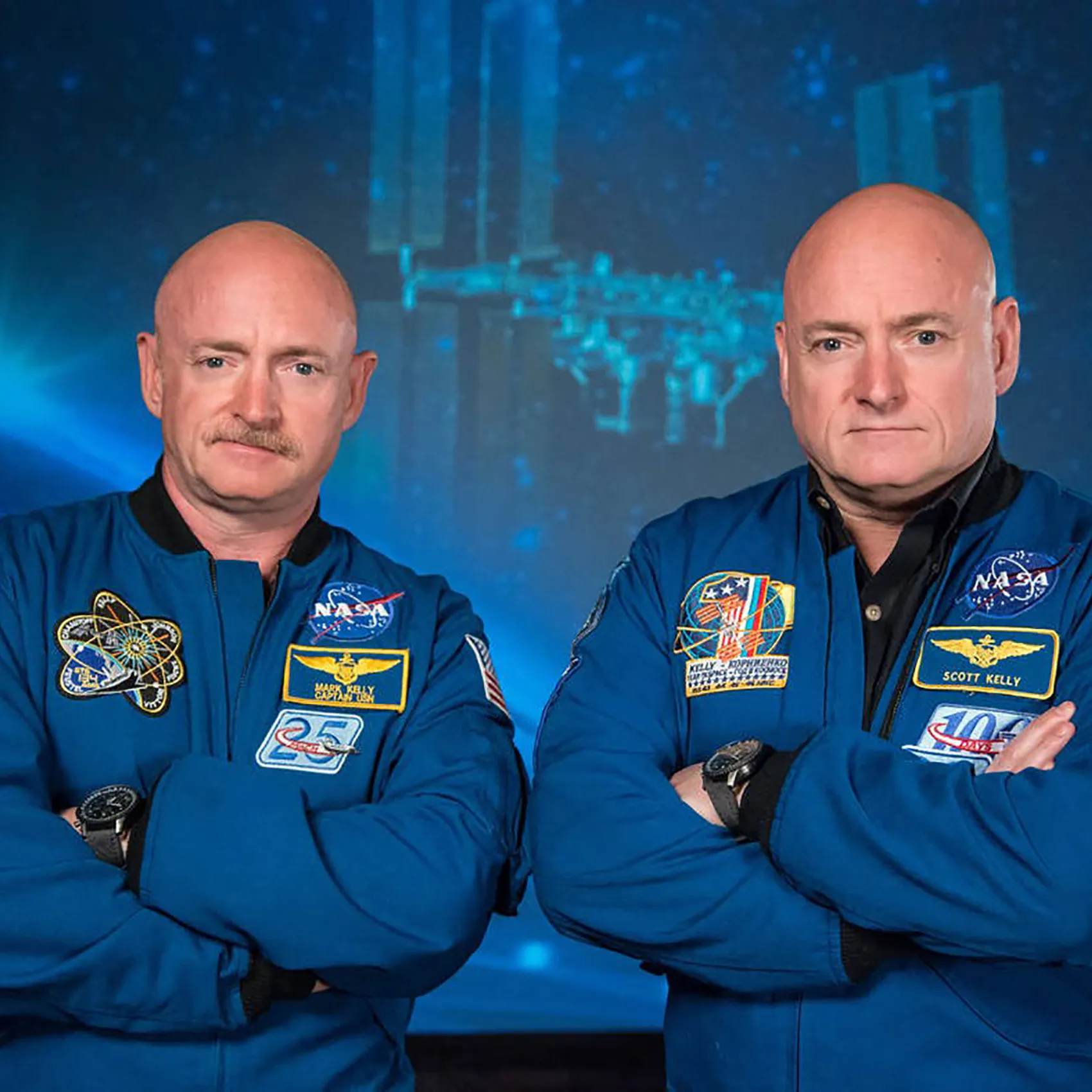 Scott and Mark Kelly in their NASA jackets with arms crossed Scott and Mark Kelly in their NASA jackets with arms crossed