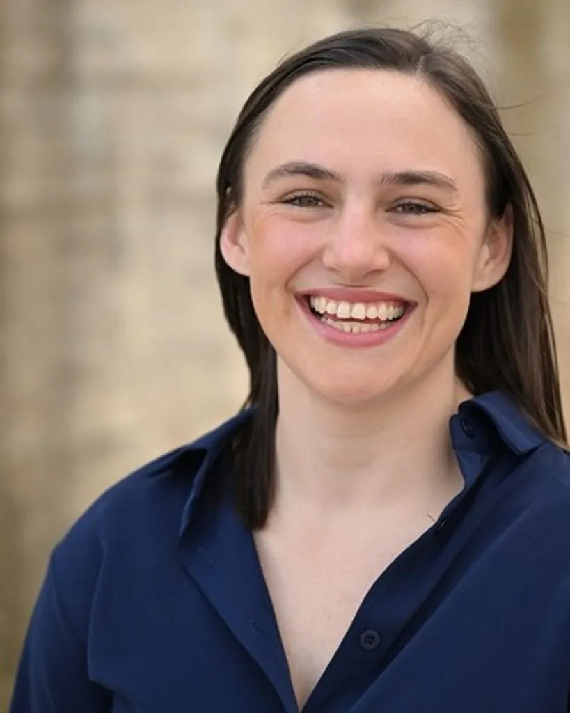 Gracey Kayla Hope Adams, a woman with dark hair and a navy shirt, smiling broadly.