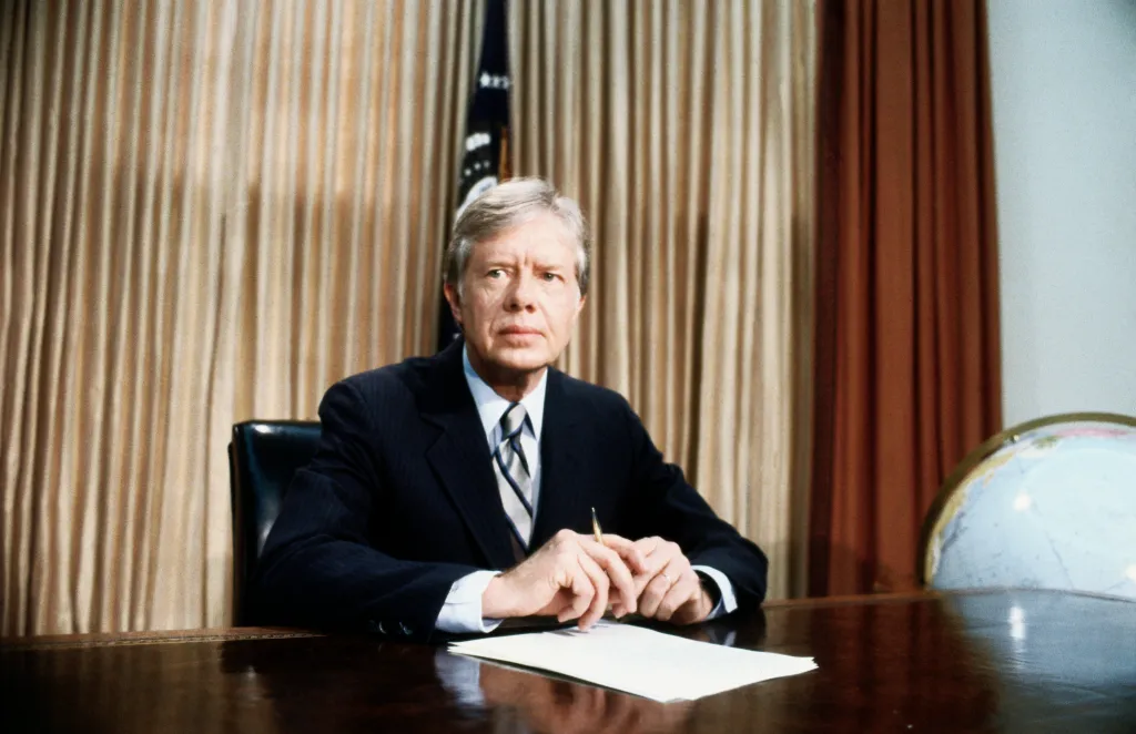 President Jimmy Carter seated at his desk in the Oval Office.