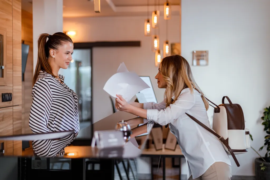 A guest at a hotel front desk checks in with a staff member.