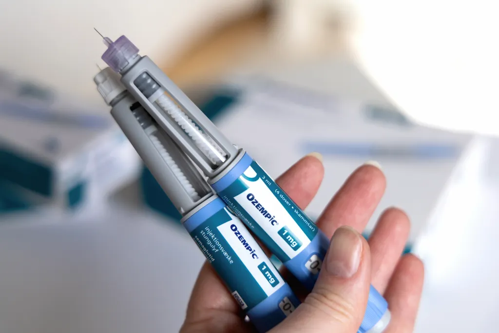 A hand holding two Ozempic insulin injection pens for diabetics.