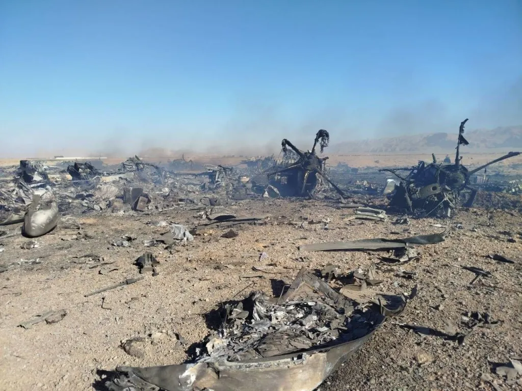 Wreckage of a downed military helicopter in a desert landscape.