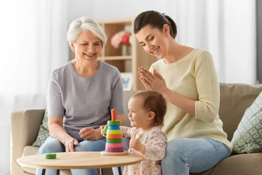Mother, baby, and grandmother playing with a stacking toy.