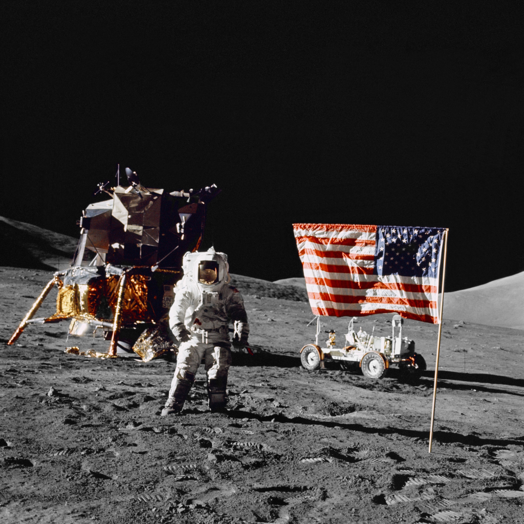 Harrison H. Schmitt, lunar module pilot, standing on the lunar surface near the United States flag during NASA's final lunar landing mission.