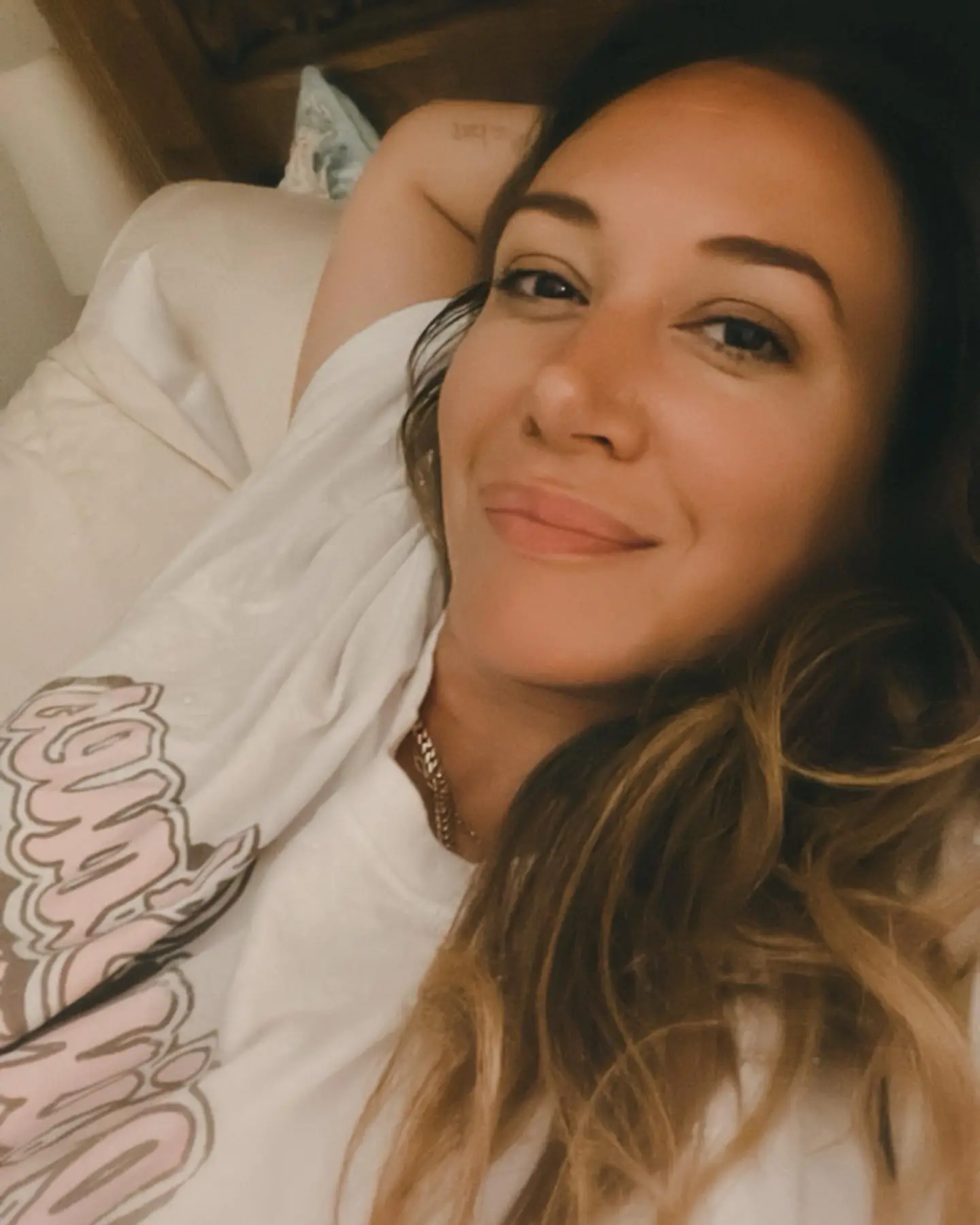 Haylie Duff lying on her back, wearing a white t-shirt, and looking at the camera.