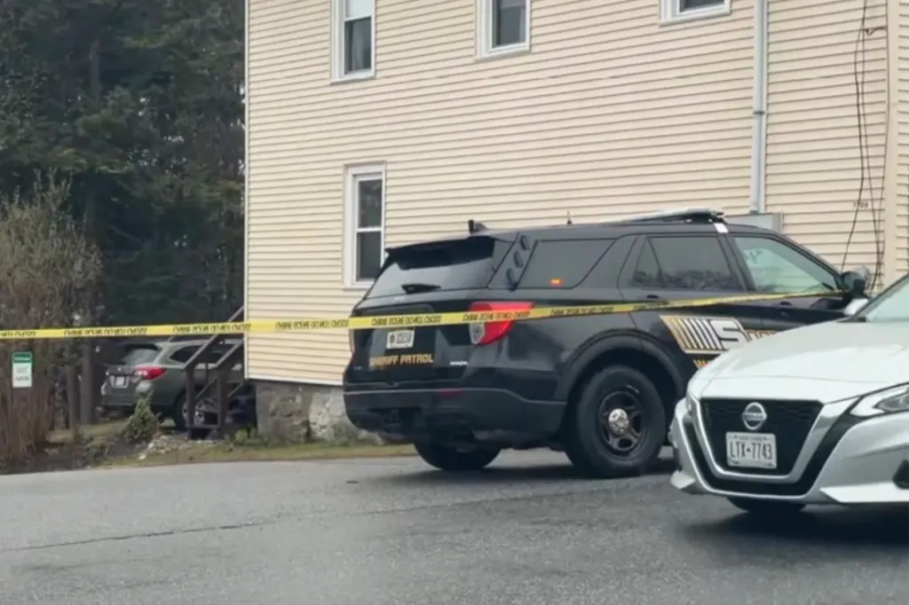 A sheriff's patrol car with yellow crime scene tape across its rear and side.