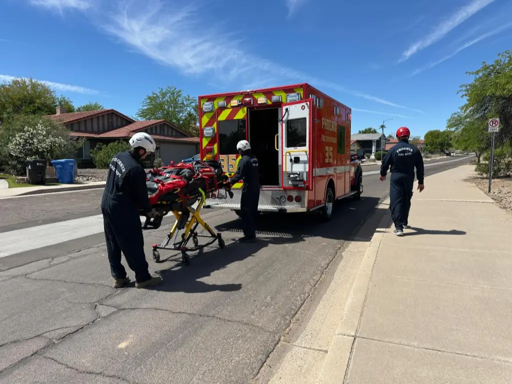 Paramedics loading a person stung by bees onto a stretcher and into a Phoenix Fire Department ambulance.