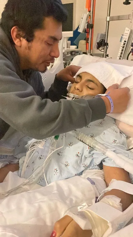 A man tending to Khimberly Zavaleta, a 12-year-old girl who suffered a brain injury after an altercation at school.