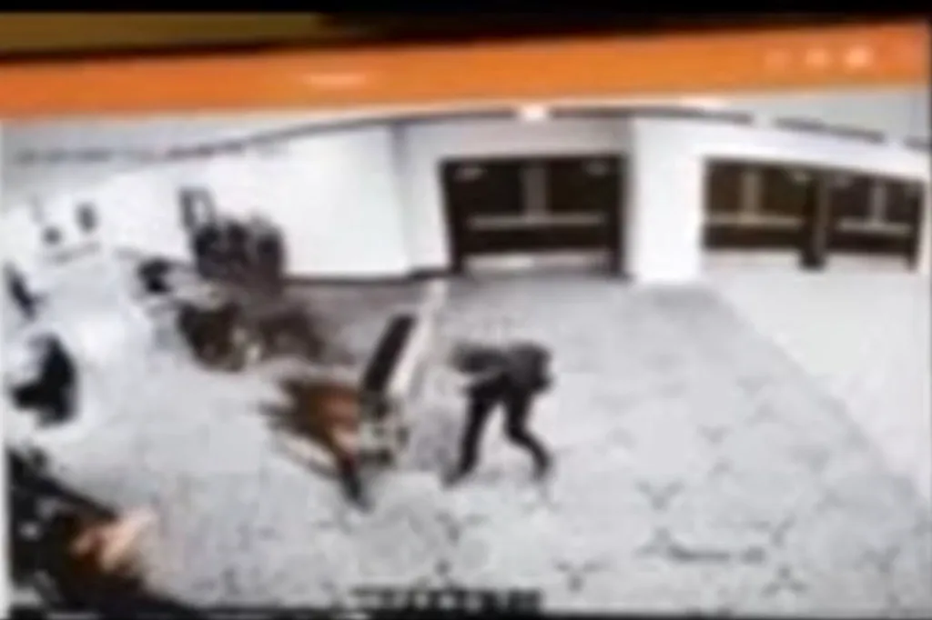 Blurred surveillance footage of a person kicking over a chair.