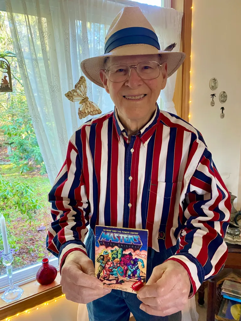 Roger Sweet, creator of He-Man and Masters of the Universe, holding a comic book.