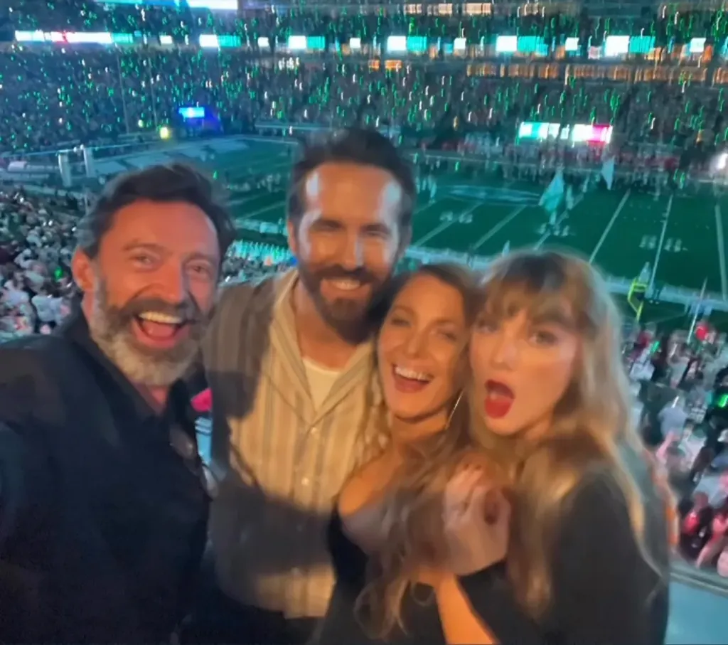 Hugh Jackman, Ryan Reynolds, Blake Lively, and Taylor Swift smile for a selfie at a Chiefs game.