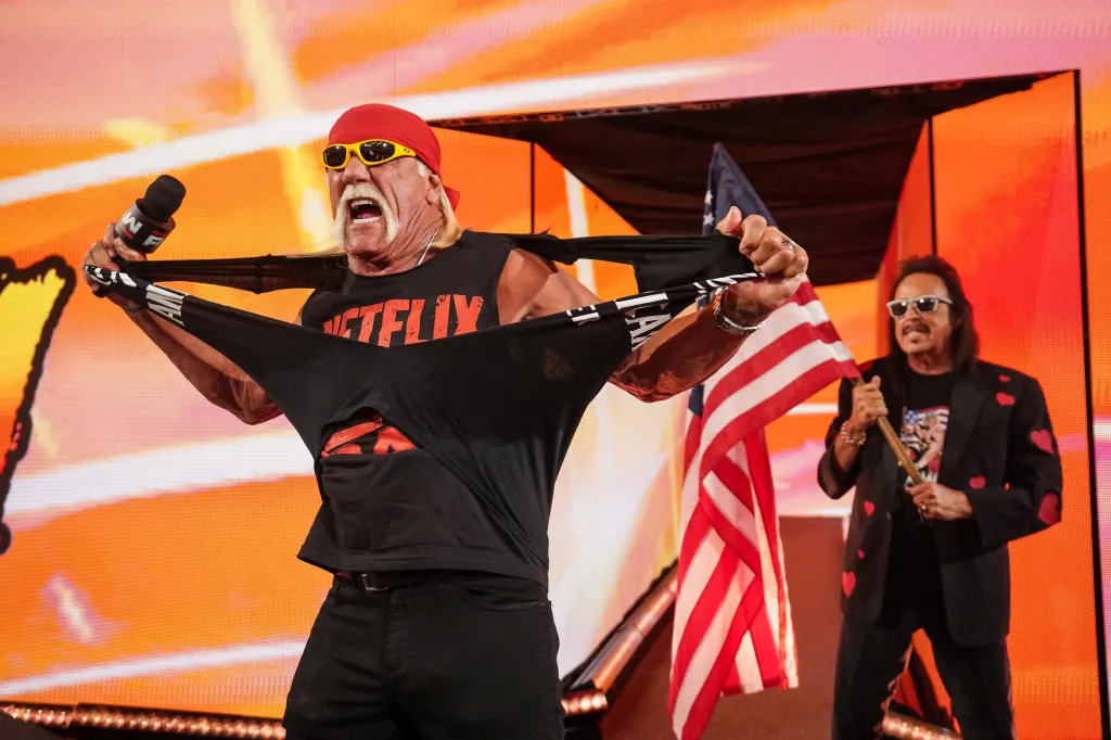 Hulk Hogan tears his Netflix shirt while speaking with Jimmy Hart on stage.