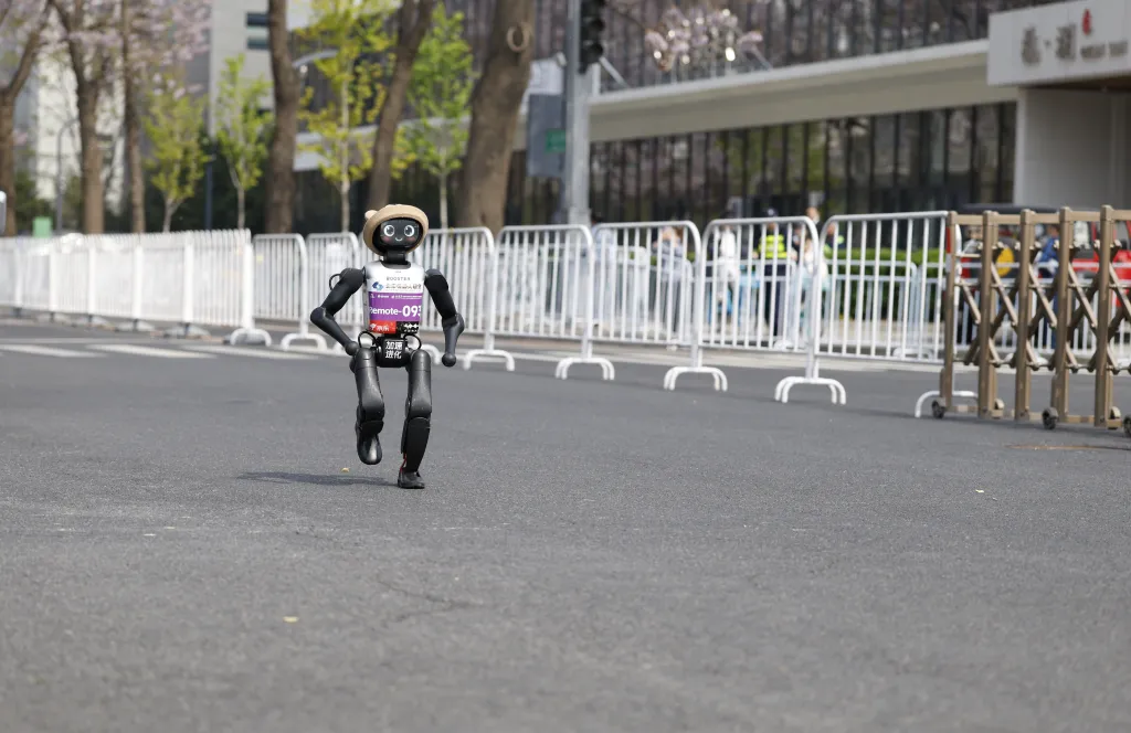 A humanoid robot wearing a beige hat and bib number 093 runs on an asphalt road during a marathon.