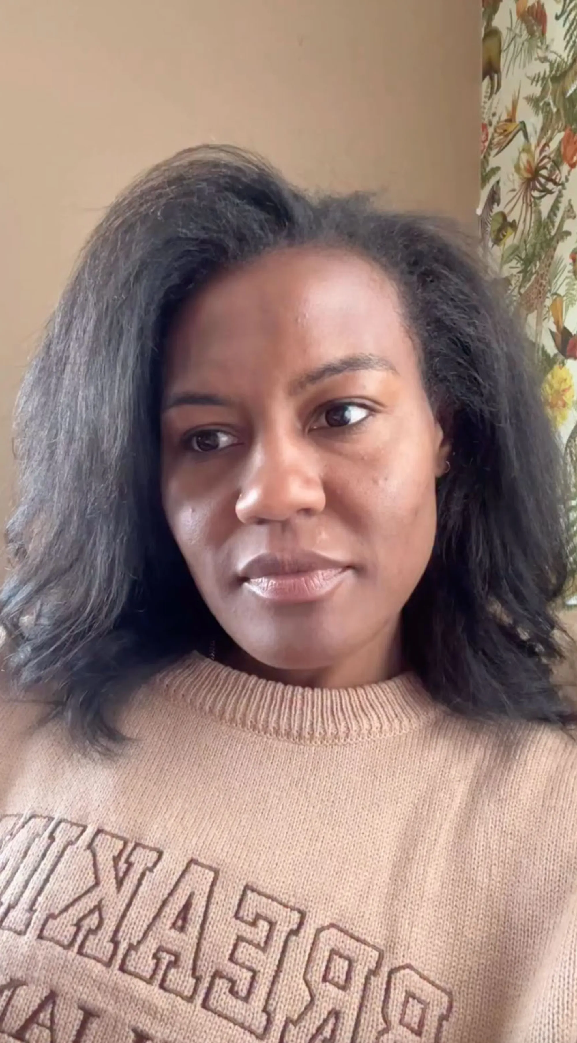 Janai Norman looking off to the side, wearing a light brown sweater.