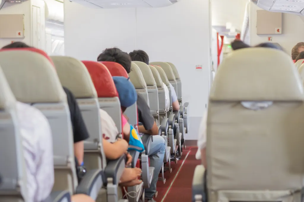 Interior of an airplane with passengers seated in economy class, waiting for take-off.
