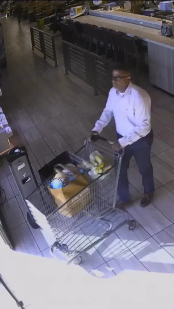 CCTV image of a man pushing a shopping cart full of stolen wine from a grocery store.