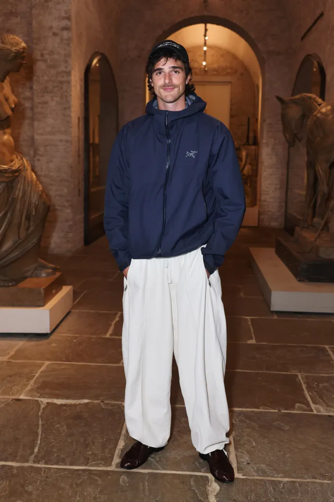 Jacob Elordi posing in a navy blue jacket, white pants, and a baseball cap at the Frankenstein BAFTA Q&A.
