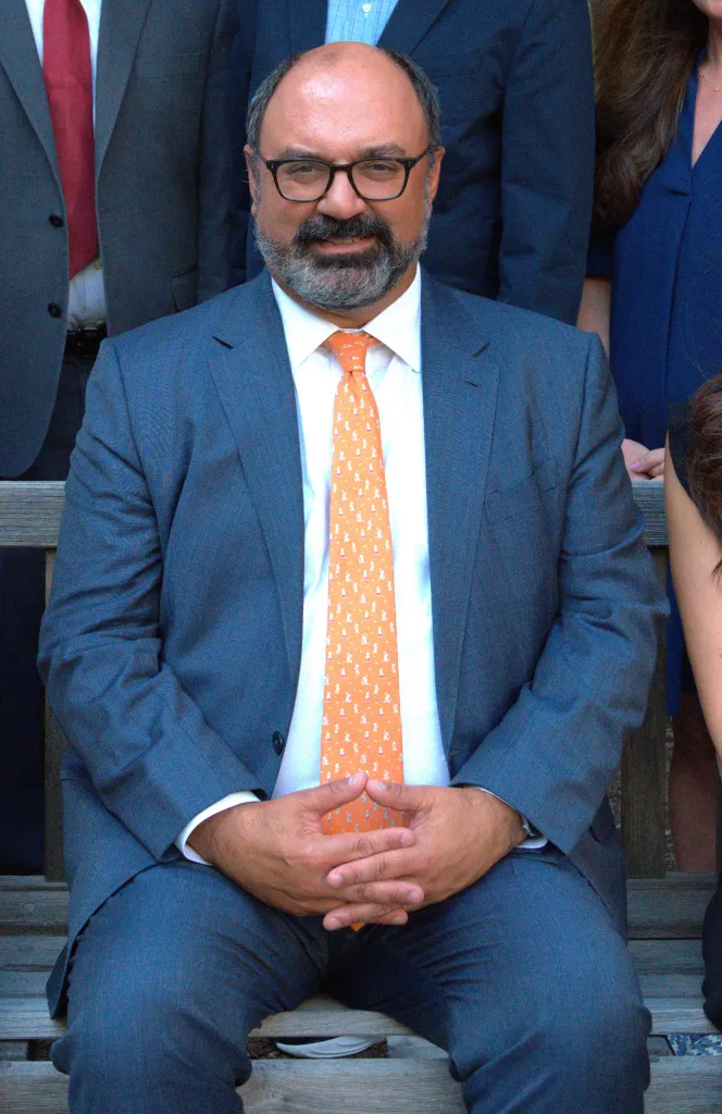 James C. Dugan, president of The Scarsdale Board of Education, wearing a suit and an orange tie.
