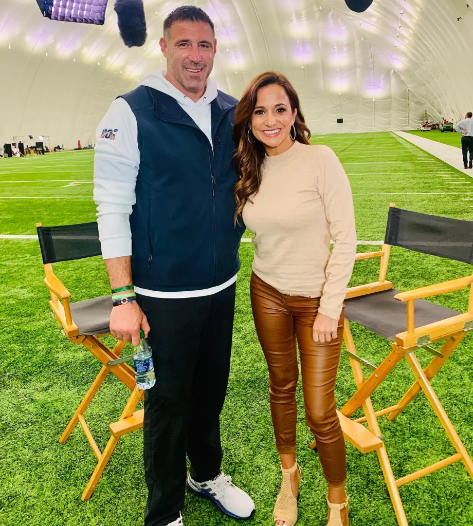 Mike Vrabel and reporter Dianna Russini pose together on an indoor football field.