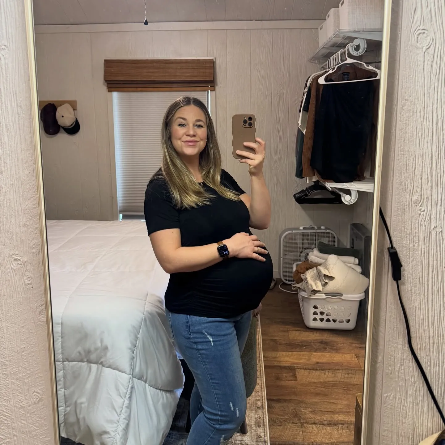 A smiling pregnant woman takes a mirror selfie.