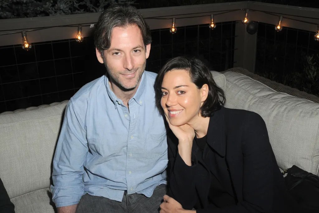 Jeff Baena and Aubrey Plaza sitting together on a couch.