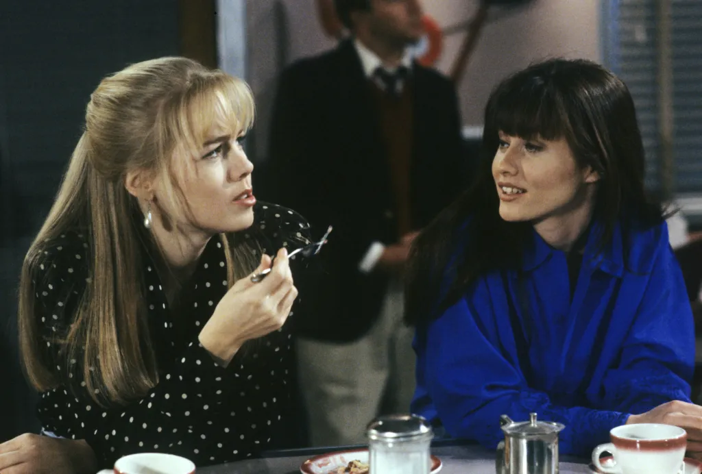 Jennie Garth and Shannen Doherty talking in a diner.