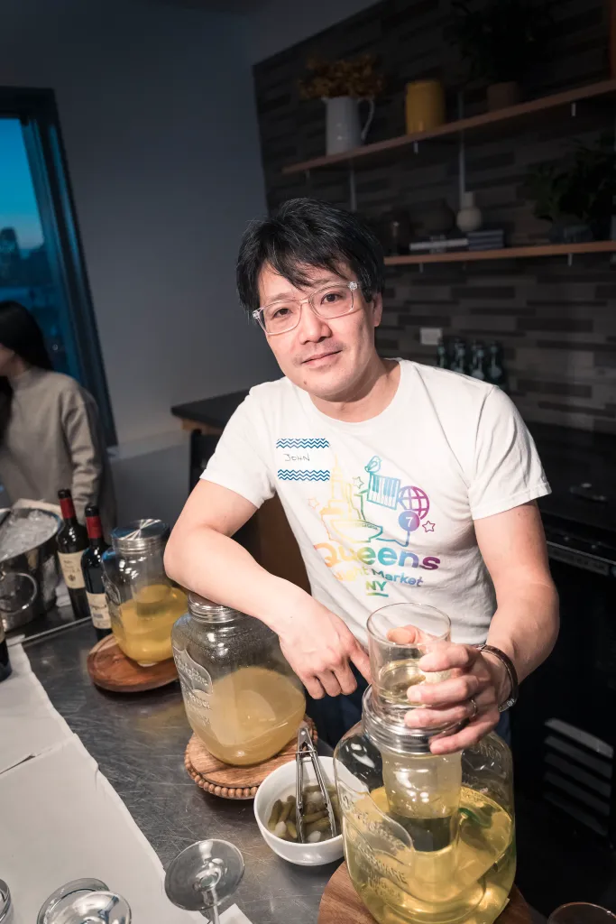 John Wang, founder of Queens Night Market, stands by a counter with drinks.