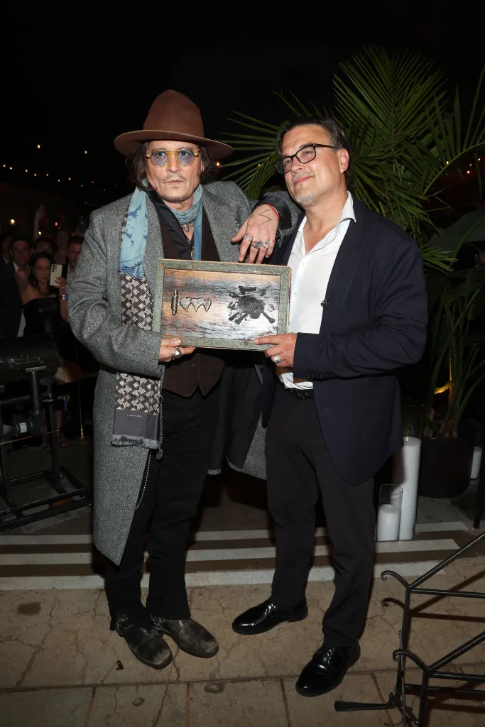 Johnny Depp and Bobby DeLeon holding a wooden plaque with the 
