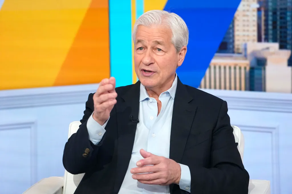Jamie Dimon, CEO of JP Morgan Chase, sits on a white chair while speaking.