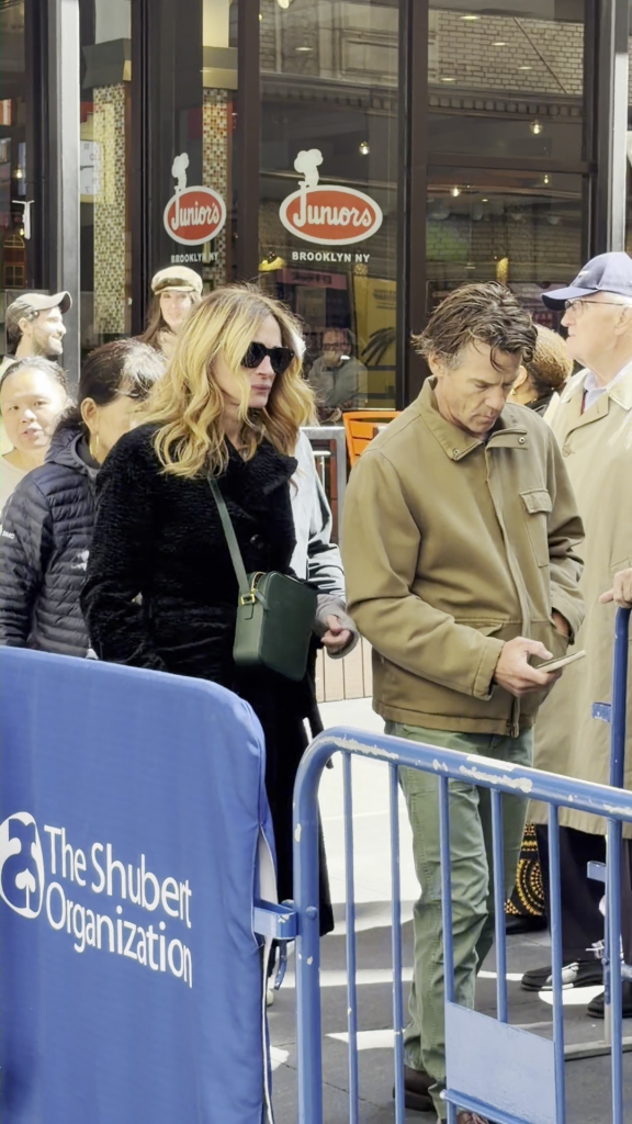 Julia Roberts and Danny Moder standing in a line in front of Juniors restaurant in Brooklyn, New York.
