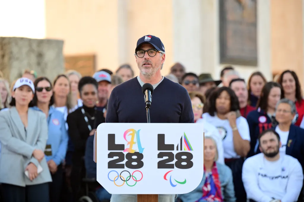 Casey Wasserman speaks at a podium with the LA28 Olympics logo during a ceremonial lighting of the LA28 Olympic cauldron.