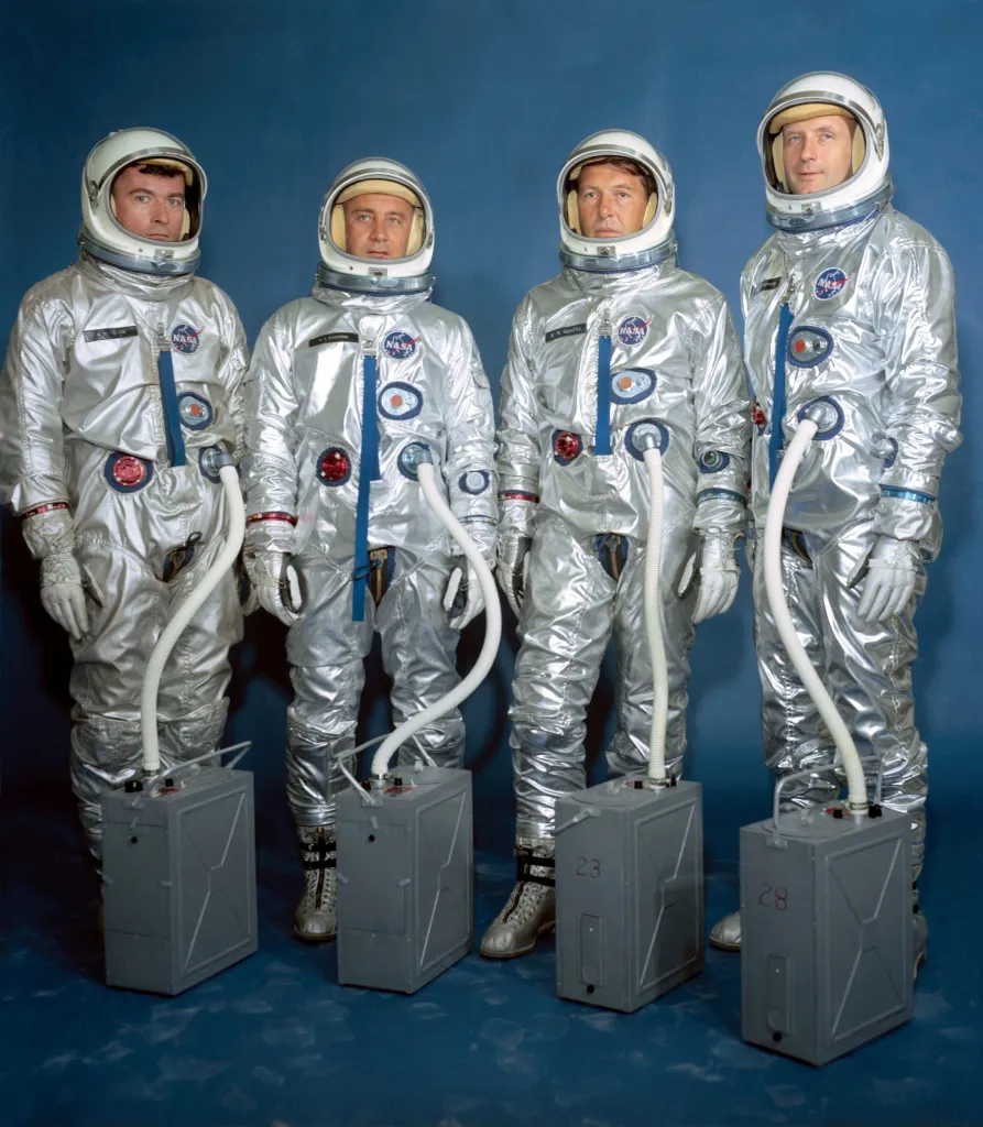Four Gemini III crew members in space suits, from left to right: John W. Young, Virgil I. Grissom, Walter M. Schirra Jr., and Thomas P. Stafford.