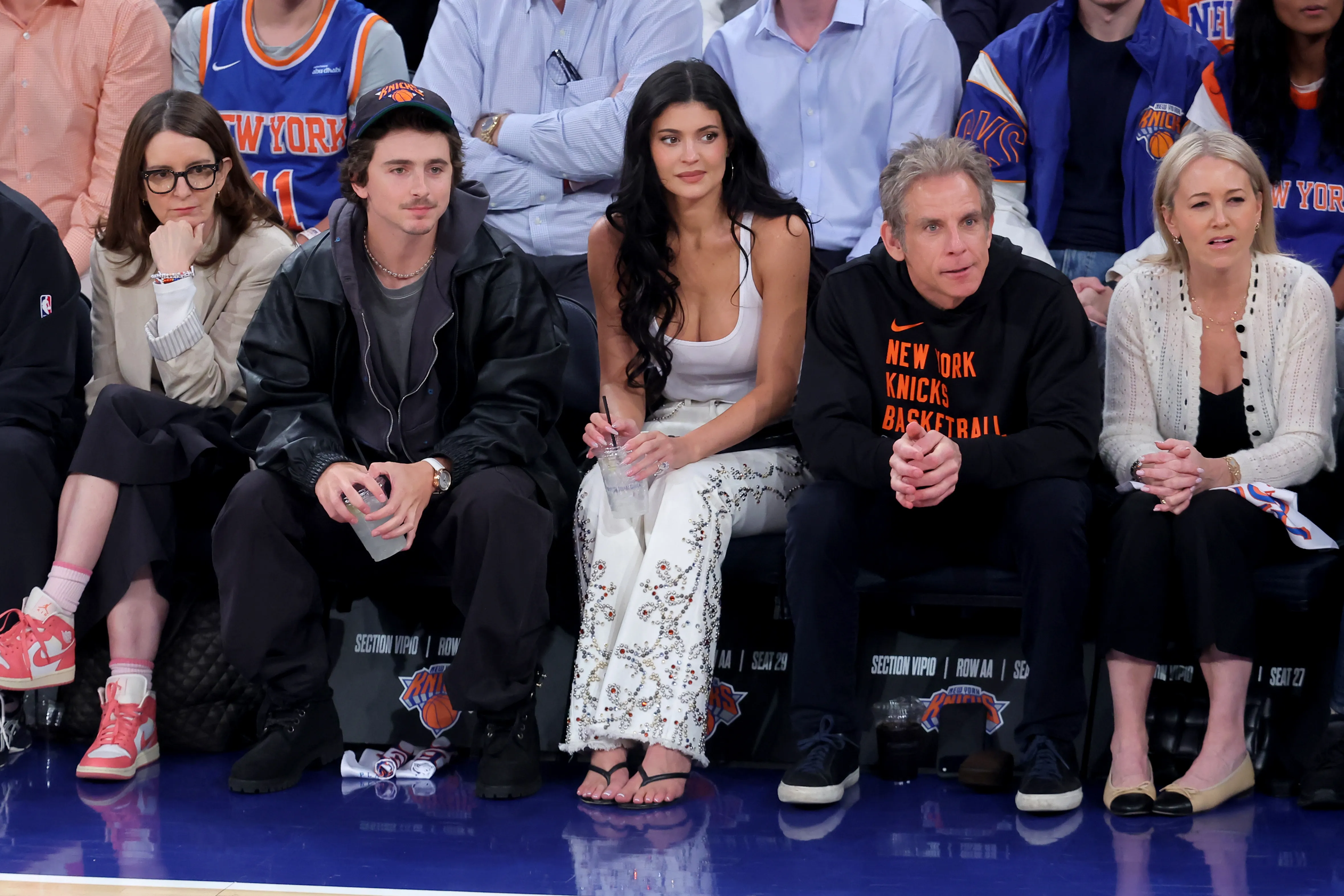Tina Fey, Timothée Chalamet, Kylie Jenner, Ben Stiller, and Christine Taylor sitting courtside at an NBA game.
