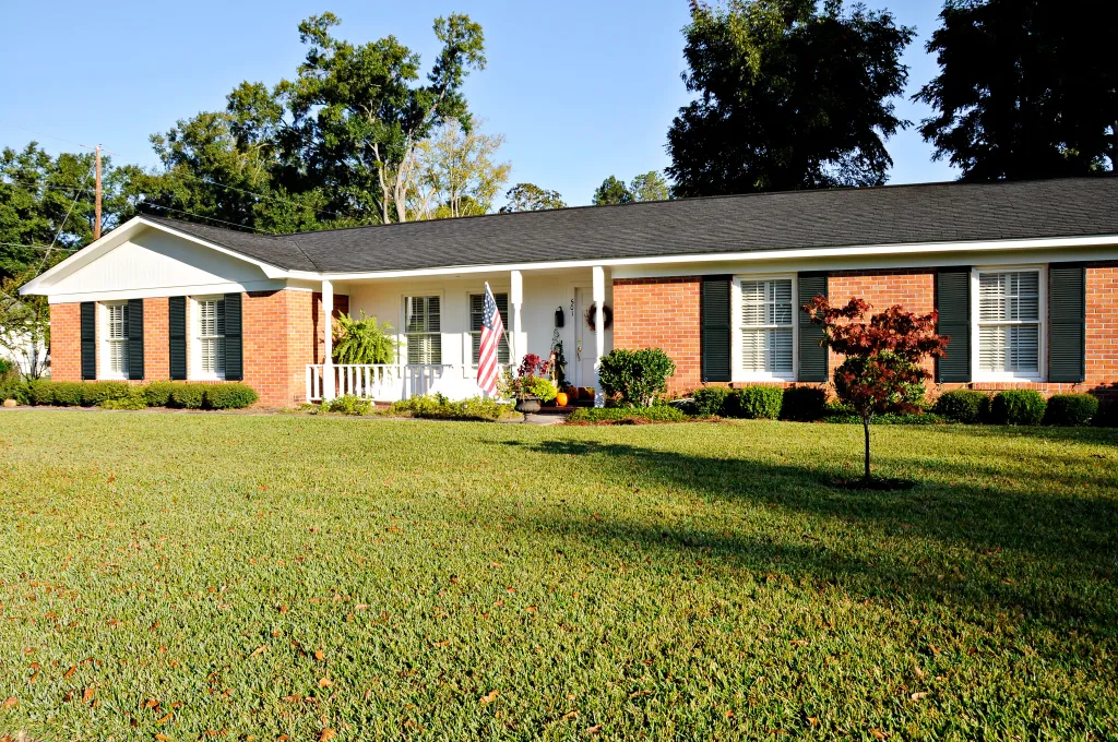 A photo of the outside of a one-level home with a lawn in front.